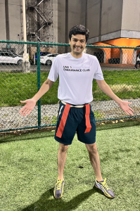 Moeez posing with flags during a game of flag football in a fenced-in area. 